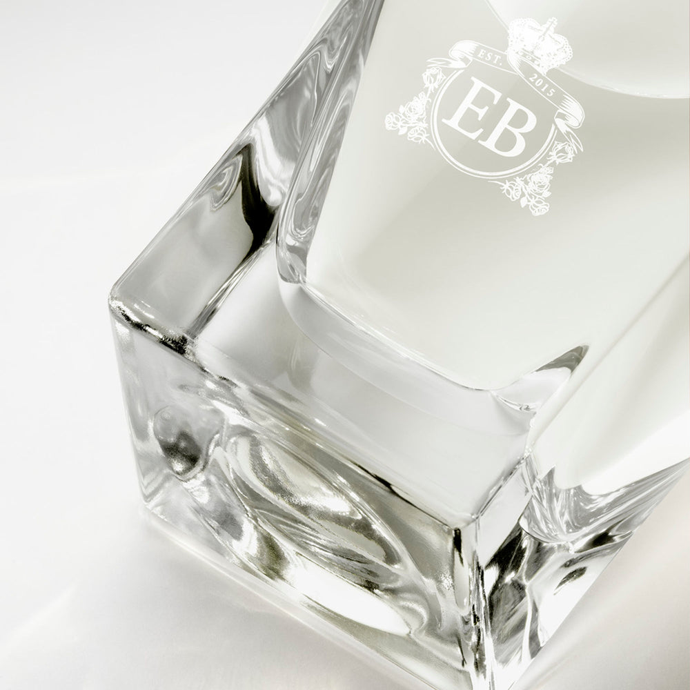 Detail of the bottom of the 100 ml bottle, with transparent glass and yellowish perfum. Detail of logo with the EB initials in white ink. Kingston Osmanthus, a fragrance by Eric Butherbaugh.