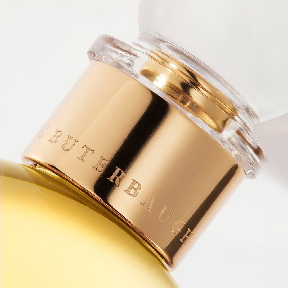 Detail of the top of the 100 ml bottle, with transparent glass and yellowish perfum. Spherical cap with gold band. Nick´s Sunflower, a fragrance by Eric Butherbaugh.