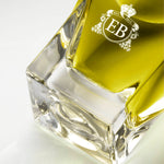 Detail of the bottom of the 100 ml bottle, with transparent glass and greenish perfum. Detail of logo with the EB initials in white ink. Apollo Hyacinth, a fragrance by Eric Butherbaugh.