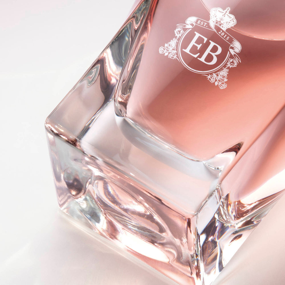 Detail of the bottom of the 100 ml bottle, with transparent glass and pinkish perfum. Detail of logo with the EB initials in white ink. Celestial Jasmine, a fragrance by Eric Butherbaugh.