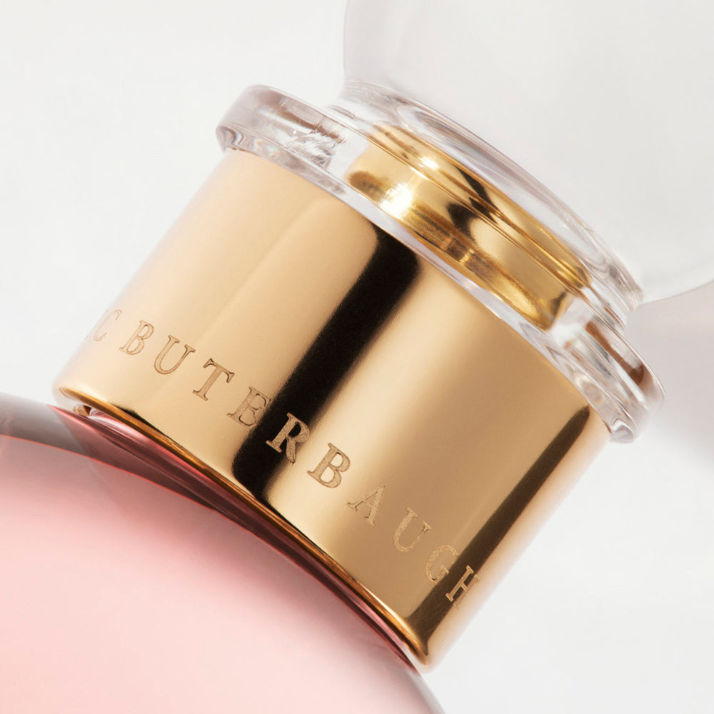 Detail of the top of the 100 ml bottle, with transparent glass and pinkish perfum. Spherical cap with gold band. Celestial Jasmine, a fragrance by Eric Butherbaugh.