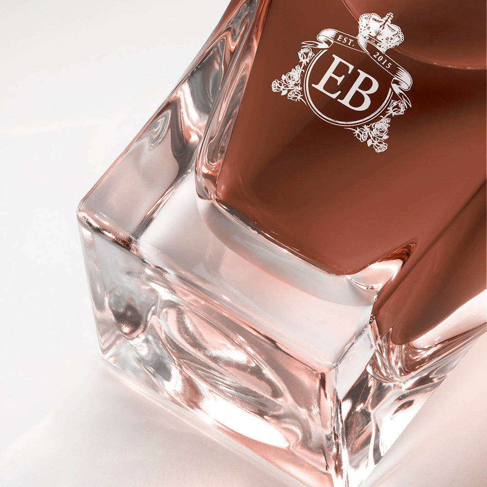 Detail of the bottom of the 100 ml bottle, with transparent glass and amber perfum. Detail of logo with the EB initials in white ink. 1947 Dalhia, a fragrance by Eric Butherbaugh.