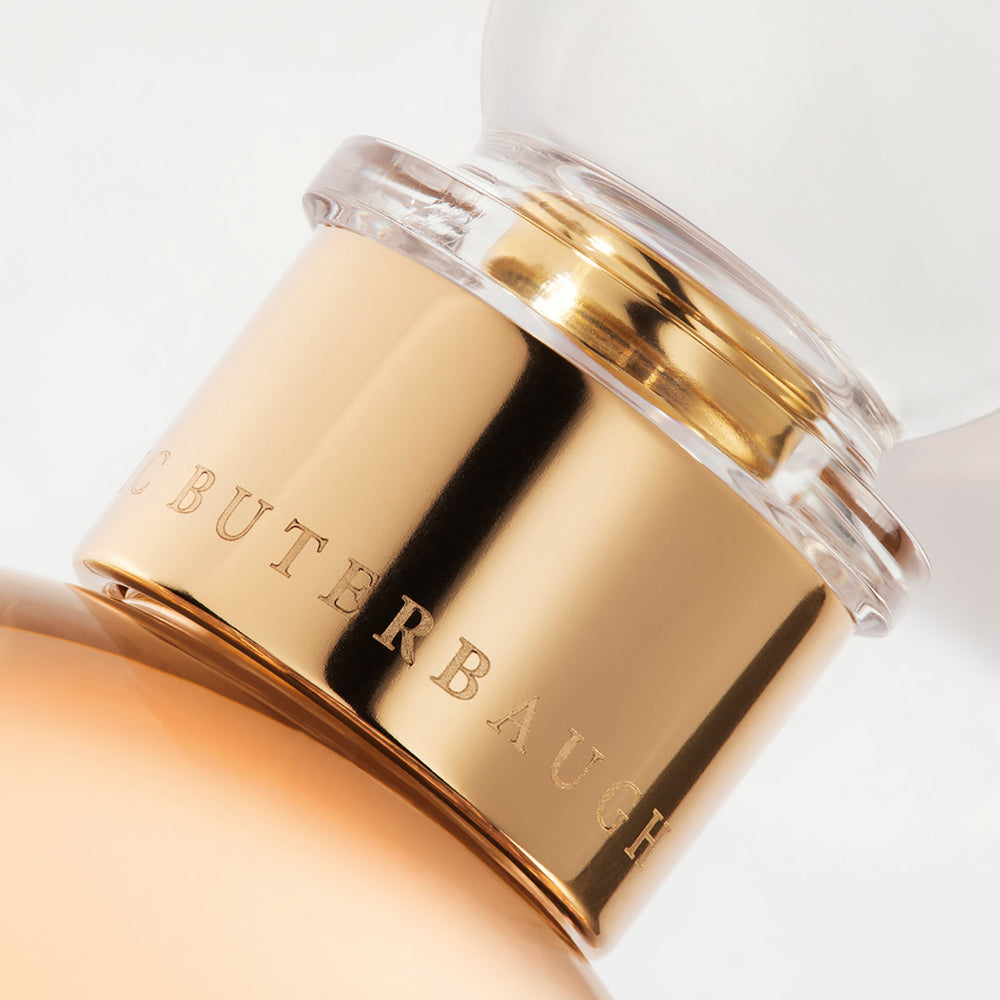 Detail of the top of the 100 ml bottle, with transparent glass and orangey perfum. Spherical cap with gold band. Maiden Orange Blossom, a fragrance by Eric Butherbaugh.