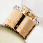 Detail of the top of the 100 ml bottle, with transparent glass and yellowish perfum. Spherical cap with gold band. Virgin Lily of the Valley, a fragrance by Eric Butherbaugh.