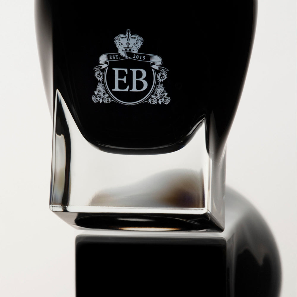 Detail of the bottom of the 100 ml bottle, with black opaque glass. Detail of logo with the EB initials in white ink. Oud Gardenia, a fragrance by Eric Butherbaugh.