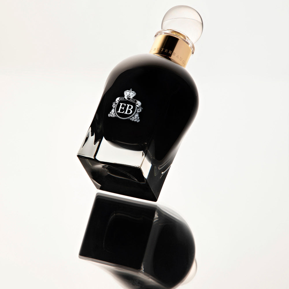 A 100 ml Oud Gardenia bottle overturning and reflecting on the ground.