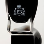 Detail of the bottom of the 100 ml bottle, with black opaque glass. Detail of logo with the EB initials in white ink. Oud Orange Flower, a fragrance by Eric Butherbaugh.