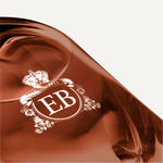 Detail of the bottom of the 250 ml bottle, with transparent glass and amber perfum. Detail of logo with the EB initials in white ink. 1947 Dalhia, a fragrance by Eric Butherbaugh.