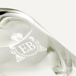Detail of the bottom of the 250 ml bottle, with transparent glass and yellowish perfum. Detail of logo with the EB initials in white ink. Kingston Osmanthus, a fragrance by Eric Butherbaugh.