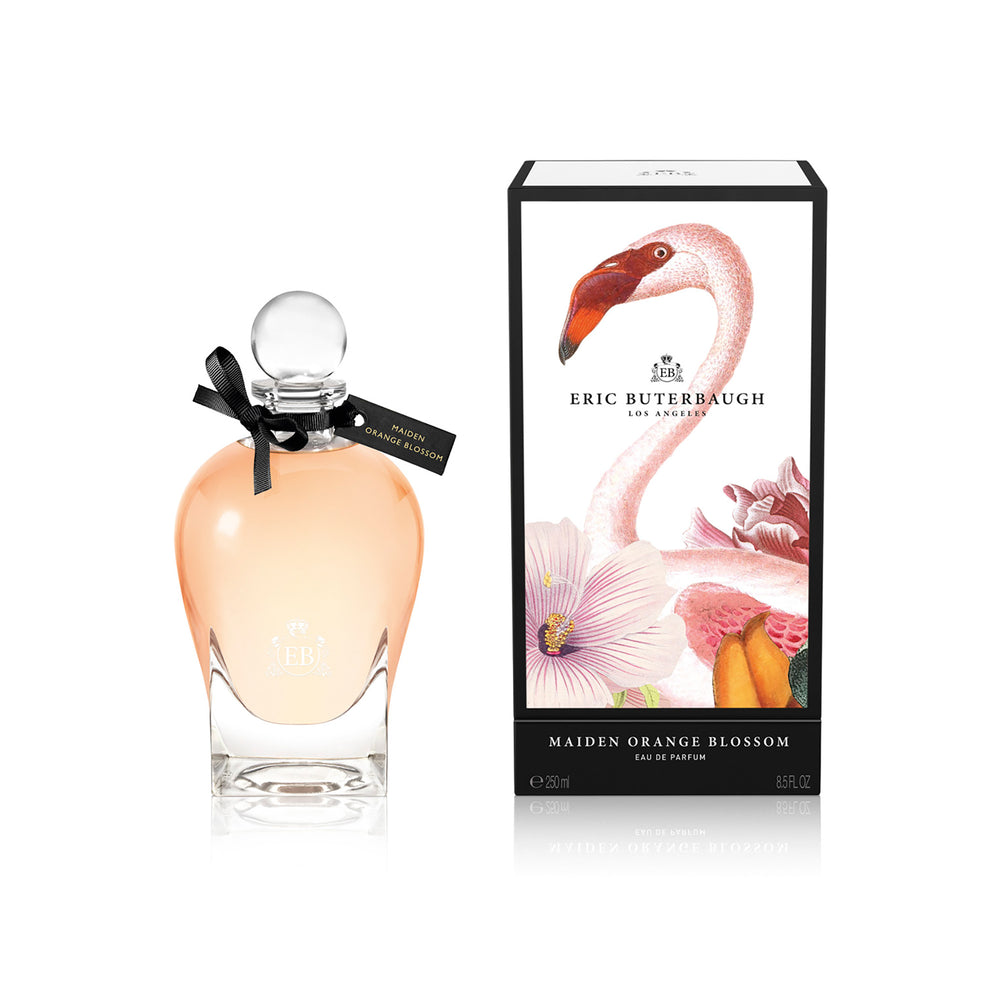 250 ml bottle, with transparent glass and orangey perfum. Spherical cap with black ribbon. By his side the box, with pink flamingo and flowers illustration, within a black border. Maiden Orange Blossom, a fragrance by Eric Butherbaugh.