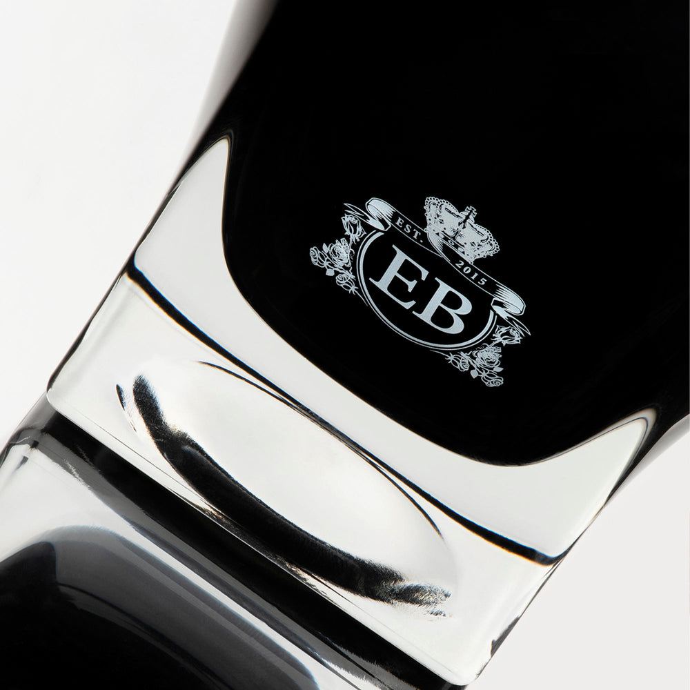 Detail of the bottom of the 250 ml bottle, with black opaque glass. Detail of logo with the EB initials in white ink. Oud Gardenia, a fragrance by Eric Butherbaugh.