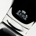 Detail of the bottom of the 250 ml bottle, with black opaque glass. Detail of logo with the EB initials in white ink. Oud Orange Flower, a fragrance by Eric Butherbaugh.