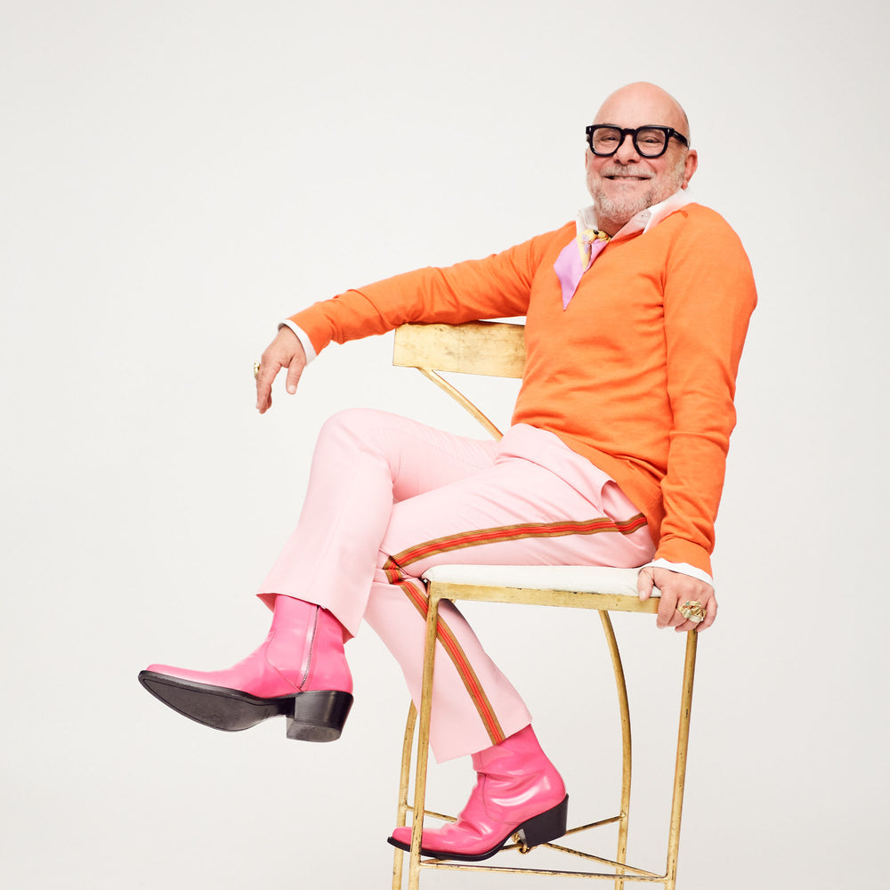 Eric Buterbaugh, dressed in color block, smiling sitting in a chair.