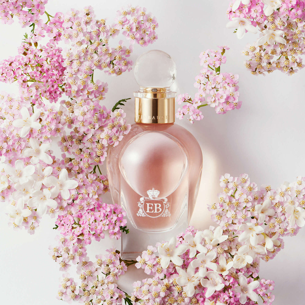 A 100 ml Celestial Jasmine bottle lying next to some pink jasmines.