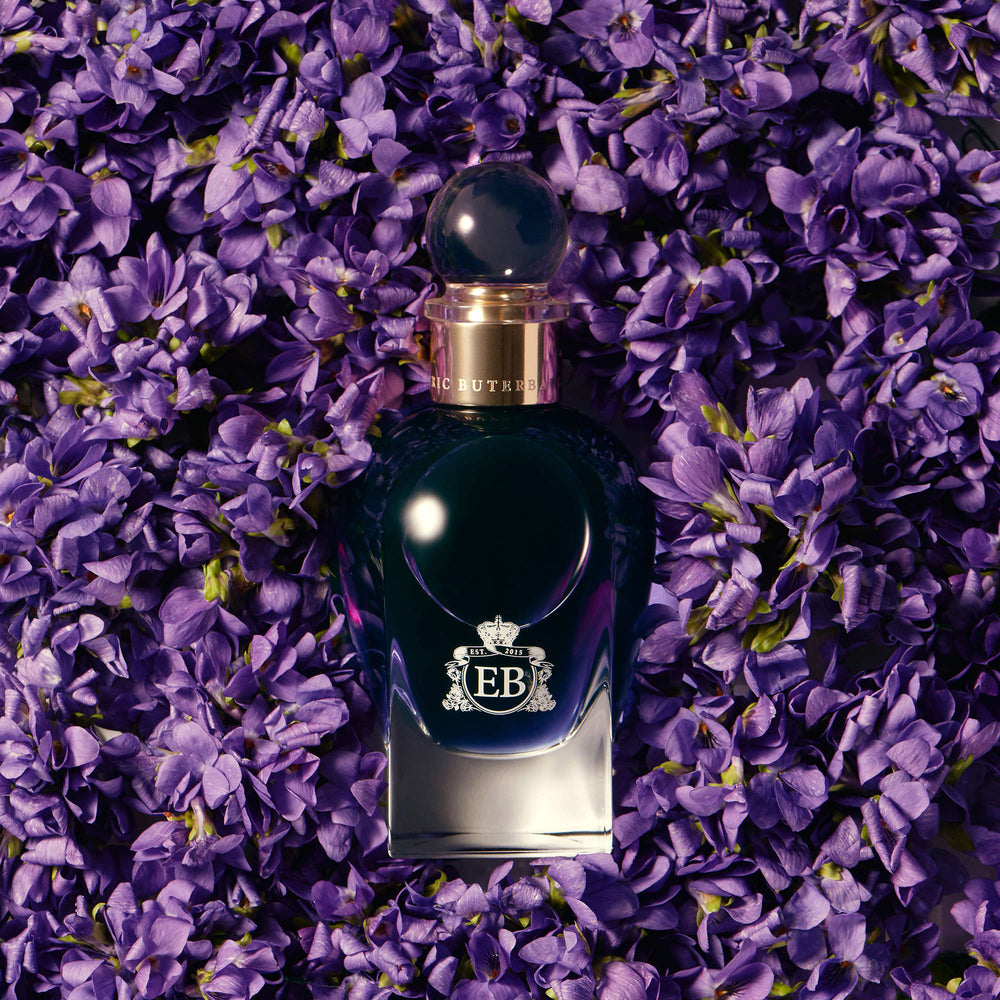 A 100 ml Fragile Violet bottle lying on a bed of violets.