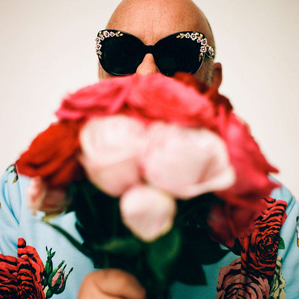 Eric Buterbaugh, with big sunglases, holding a pink roses bouquet.