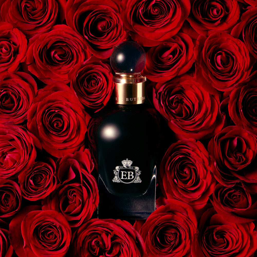 A 100 ml Oud Rose bottle lying on a bed of red roses.